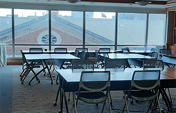 Tables and chairs in front of the big window in Rm 527 of the HSL